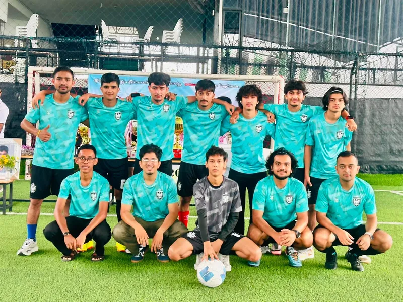 The squad in teal lined up in front of the goal, the trophies behind them
